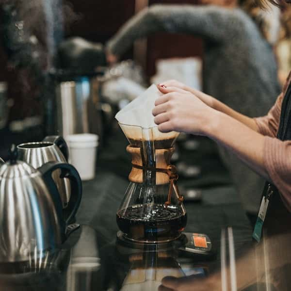 An over-head shot of someone making a latte with frothed milk from a jug